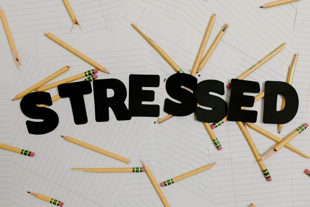 Stylized word 'stressed' with scattered pencils on paper, symbolizing anxiety and burnout.